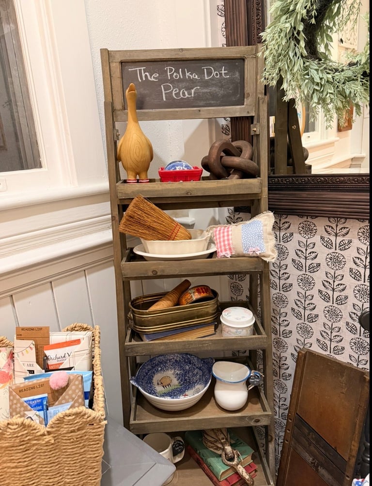 Wooden shelf unit displaying kitchen items and decor with a chalkboard sign reading The Polka Dot Pear