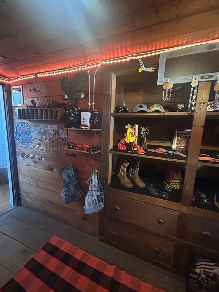 Garage interior with wooden shelving units displaying collectibles, boots, and accessories under orange neon lighting
