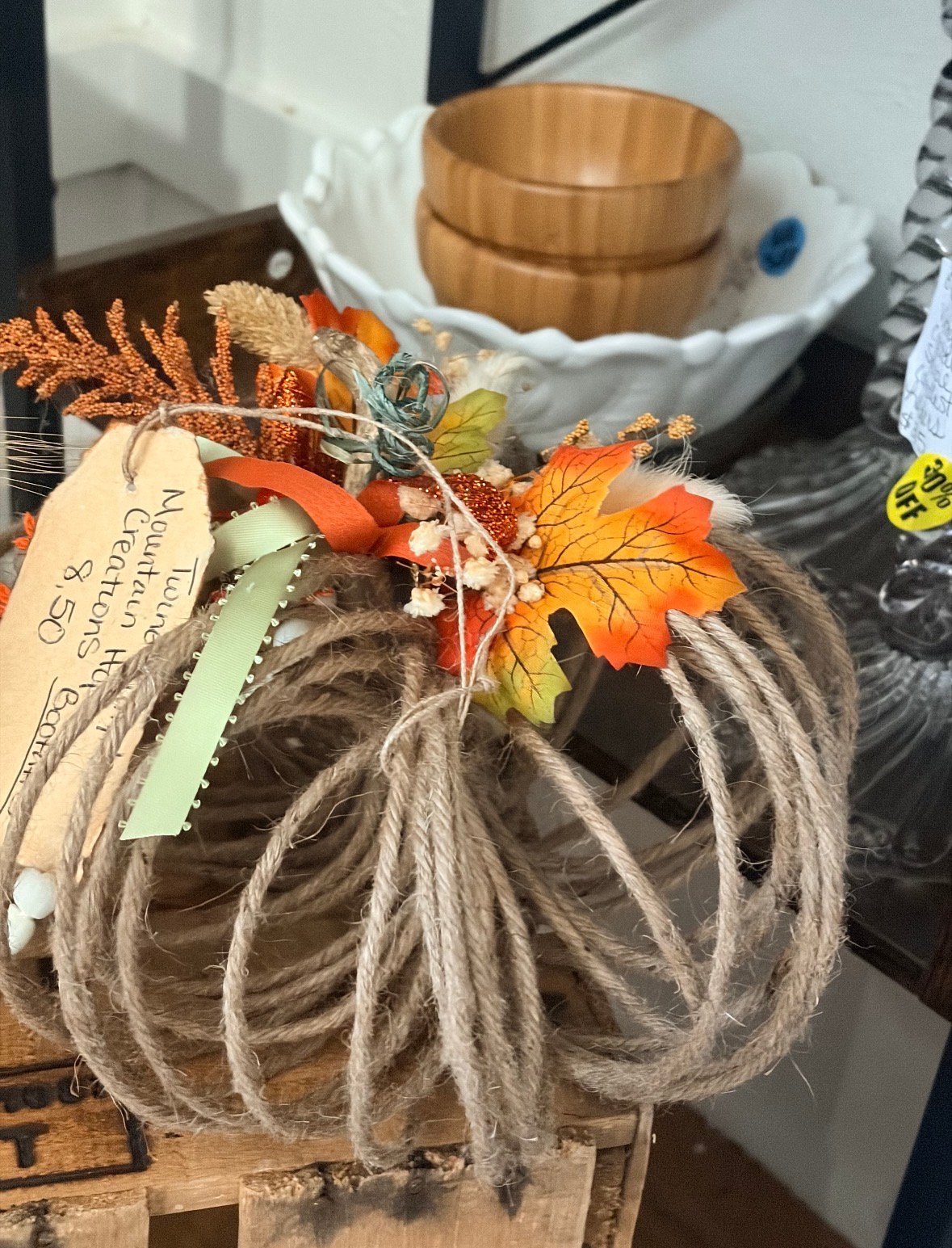 Coiled jute rope decorated with autumn leaves, dragonfly, and a kraft paper tag on display