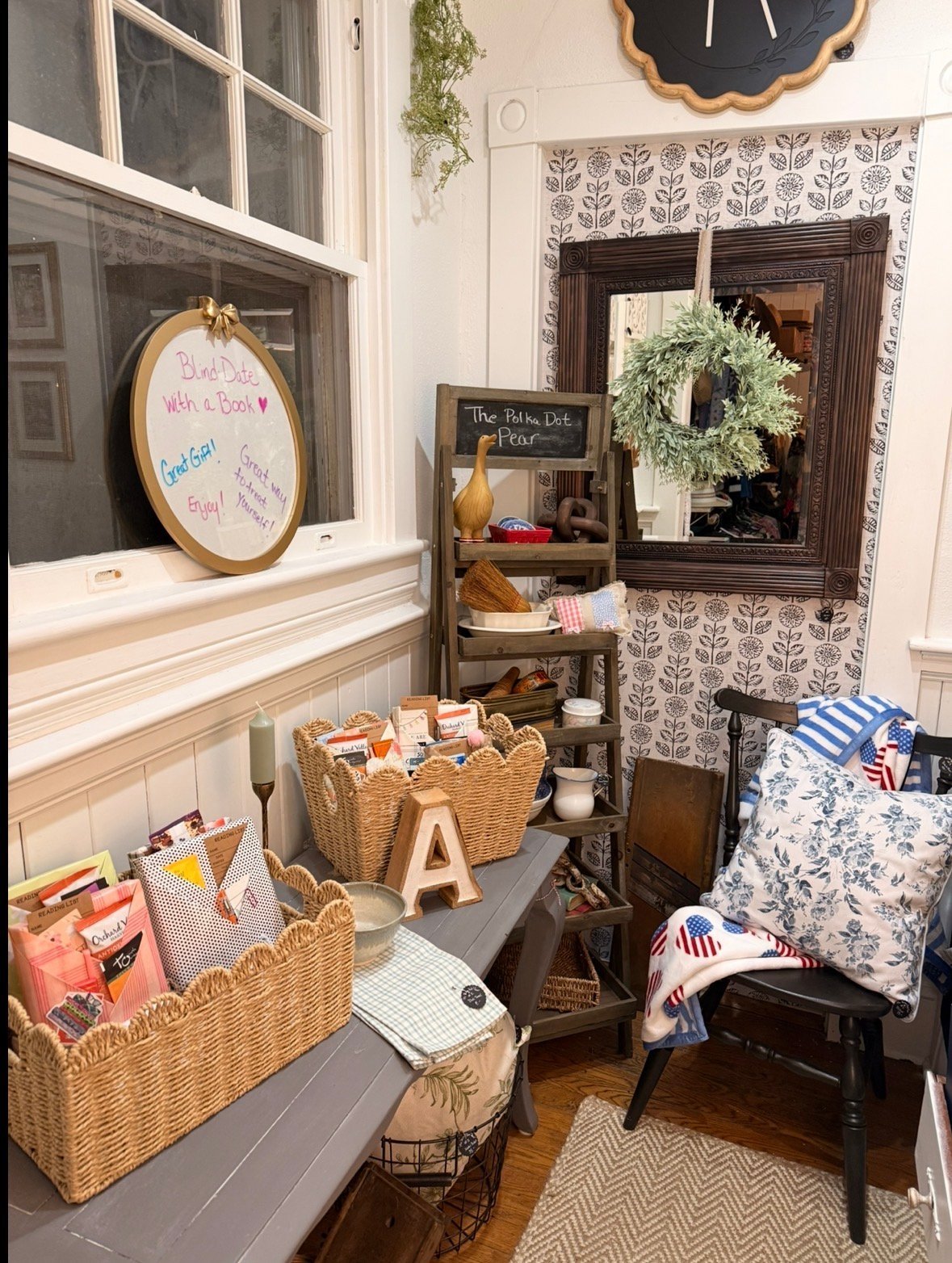 Cozy entryway with wicker baskets, wooden ladder shelf, framed mirror with wreath, and decorative pillows on a small chair
