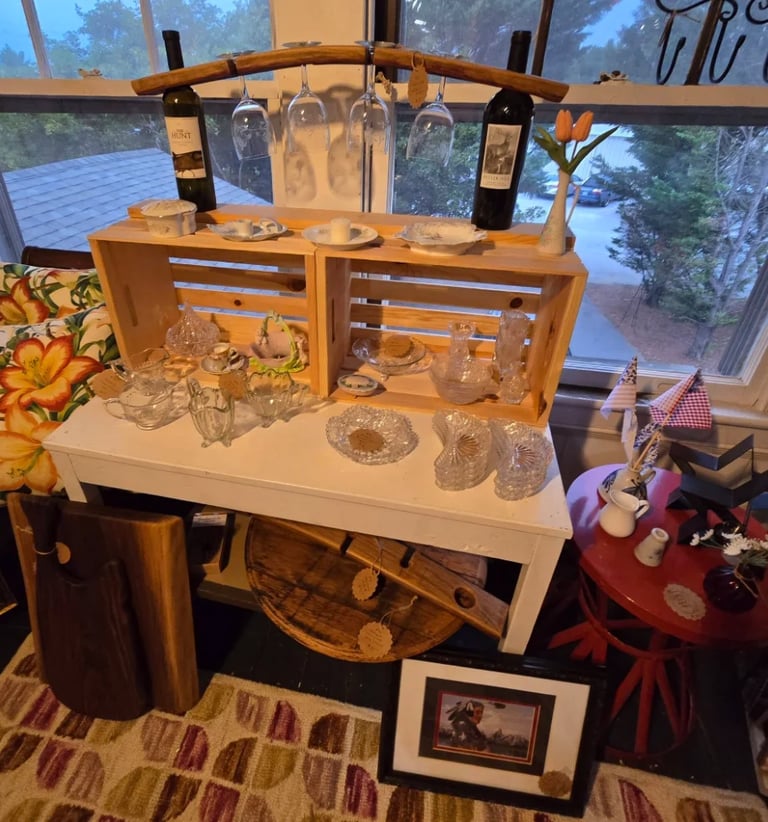Display counter with wooden cabinetry showing vintage glassware collection and decorative items against large windows