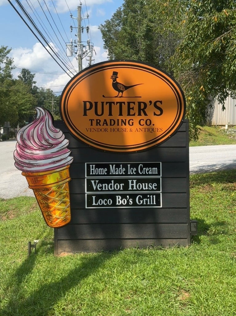 Roadside sign for Putters Trading Co. featuring an ice cream cone graphic and advertising Home Made Ice Cream, Vendor House, and Loco Bos Grill