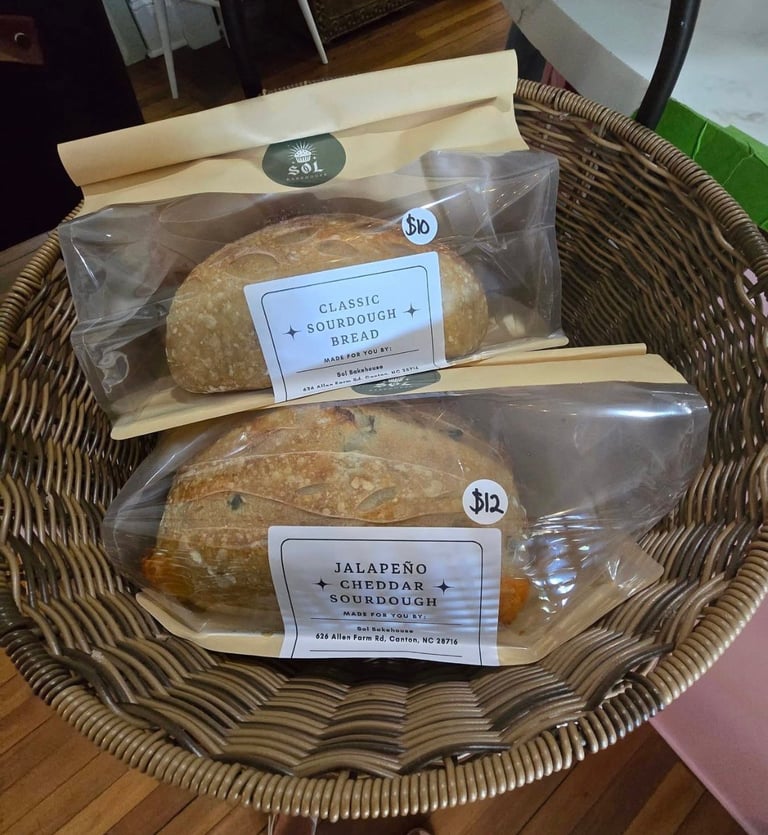 Two packaged sourdough breads in a woven basket, labeled Classic Sourdough Bread and Jalapeno Cheddar Sourdough from SOL Bakehouse