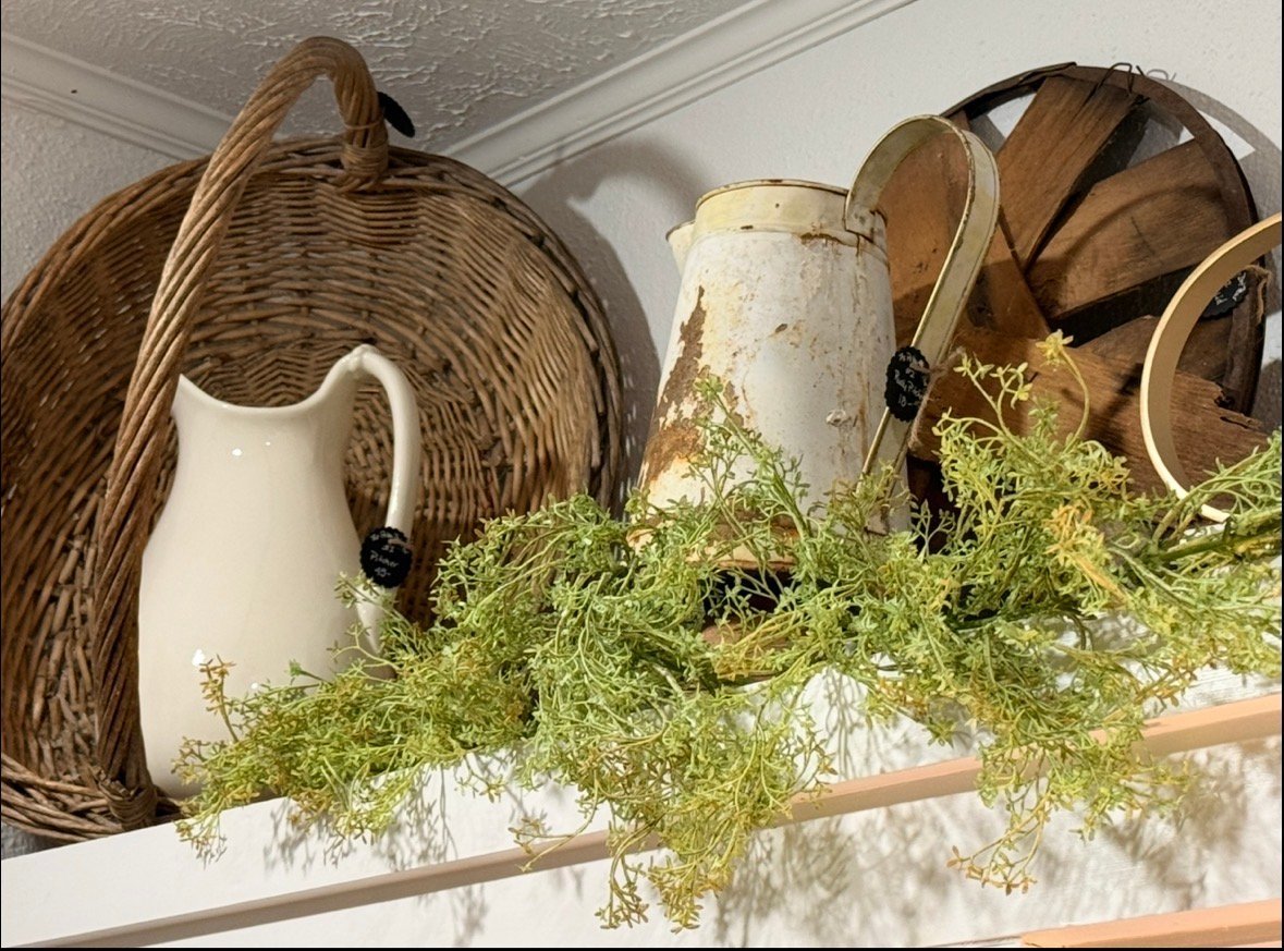 Decorative shelf display with woven baskets, white ceramic pitcher, wooden items, and fresh green trailing plant