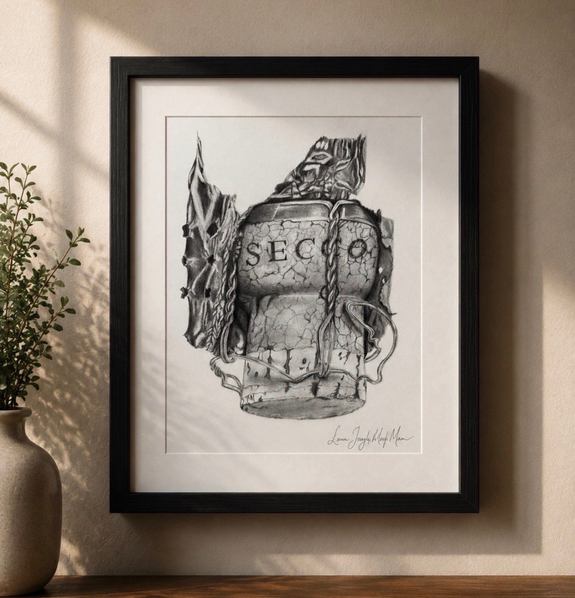 Framed black and white pen sketch of a vintage wine bottle labeled SECO with decorative foliage and vines, mounted in black frame on white wall