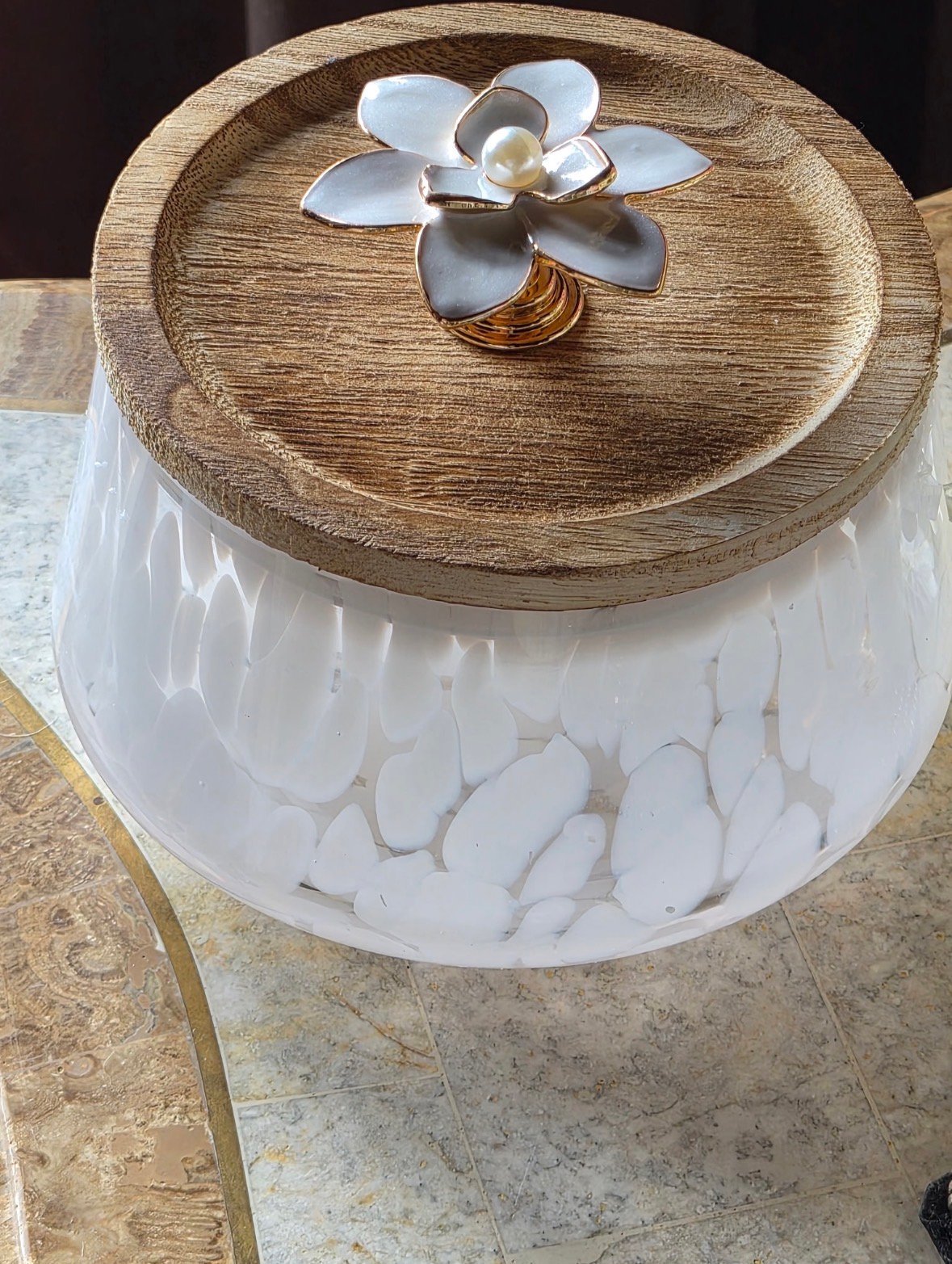 Wooden decorative box with white interior filled with white petals, topped with a metal flower ornament