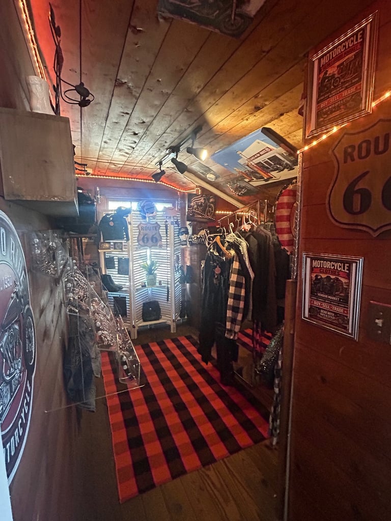 Interior of a Route 66 themed shop with red and black checkered floor, vintage signs, motorcycle memorabilia, and clothing racks
